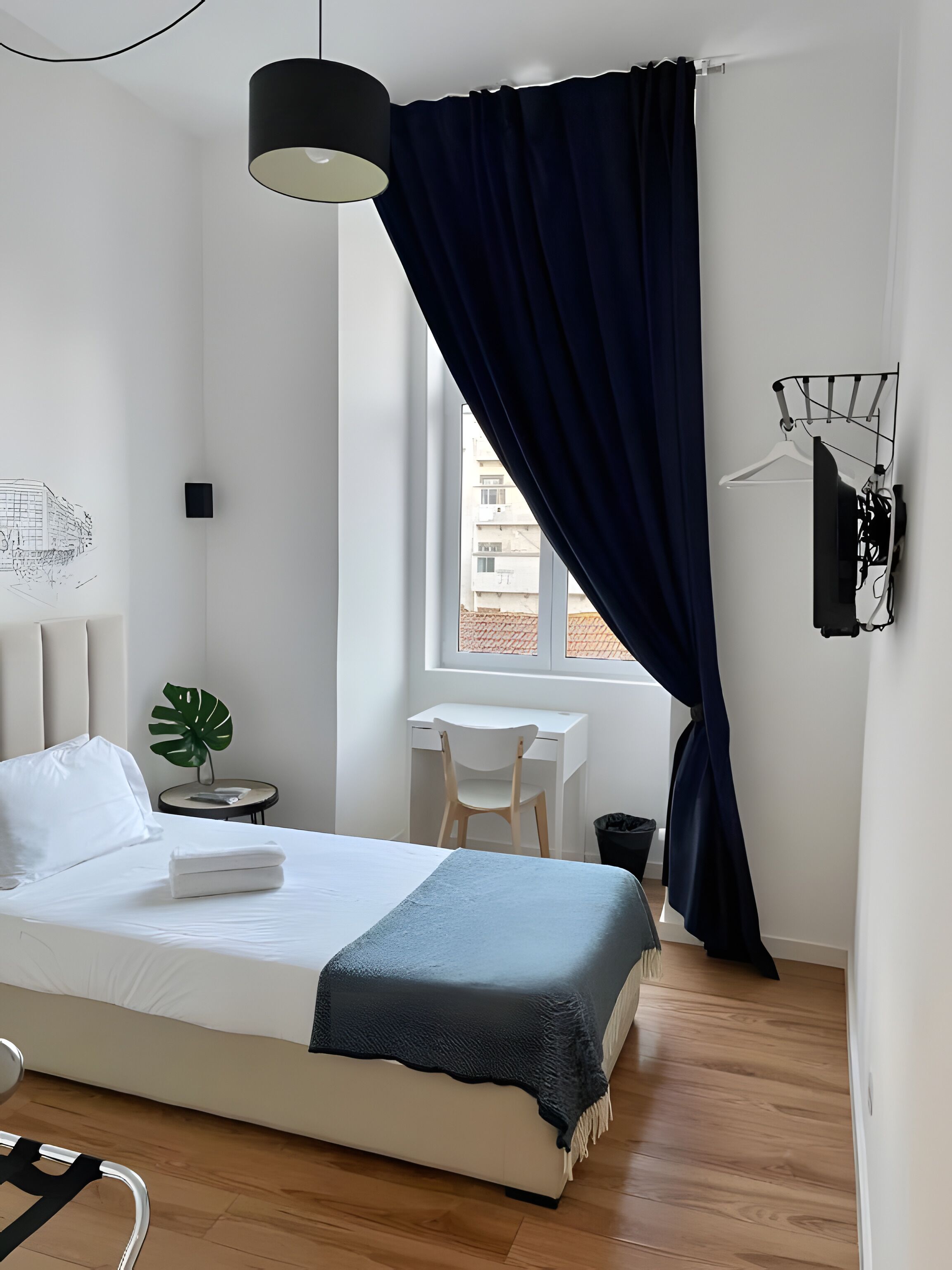 A modern bedroom with a bed, bedside table, chair, and a desk.