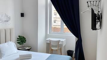 A modern bedroom with a bed, bedside table, chair, and a desk.