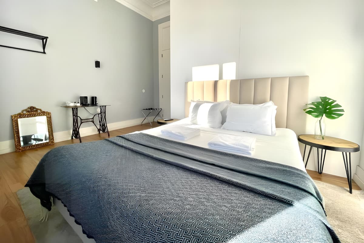 A modern hotel room with a large bed, bedside tables, a desk, and a mirror.