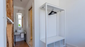A walk-in closet with a hanging rack, a mirror, and a sink in a hallway. - Lisbon Check-In Guesthouse (Lisbon)