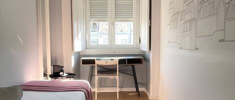 A bedroom with a bed, desk, and a wall-mounted TV.