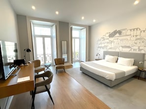 A modern hotel room with a large bed, a desk, two chairs, and a cityscape mural on the wall. - Lisbon Check-In Guesthouse (Lisbon)
