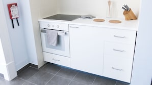 A modern kitchen with a built-in oven, a stovetop, and a countertop with a knife block and coasters. - Lisbon Check-In Guesthouse (Lisbon)
