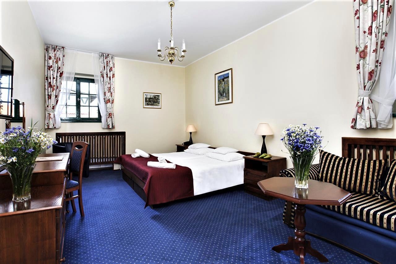 Een hotelkamer met een bed, een slaapbank, een eettafel en een kroonluchter.