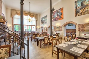 A spacious dining area with high ceilings, large windows, and a variety of seating arrangements.