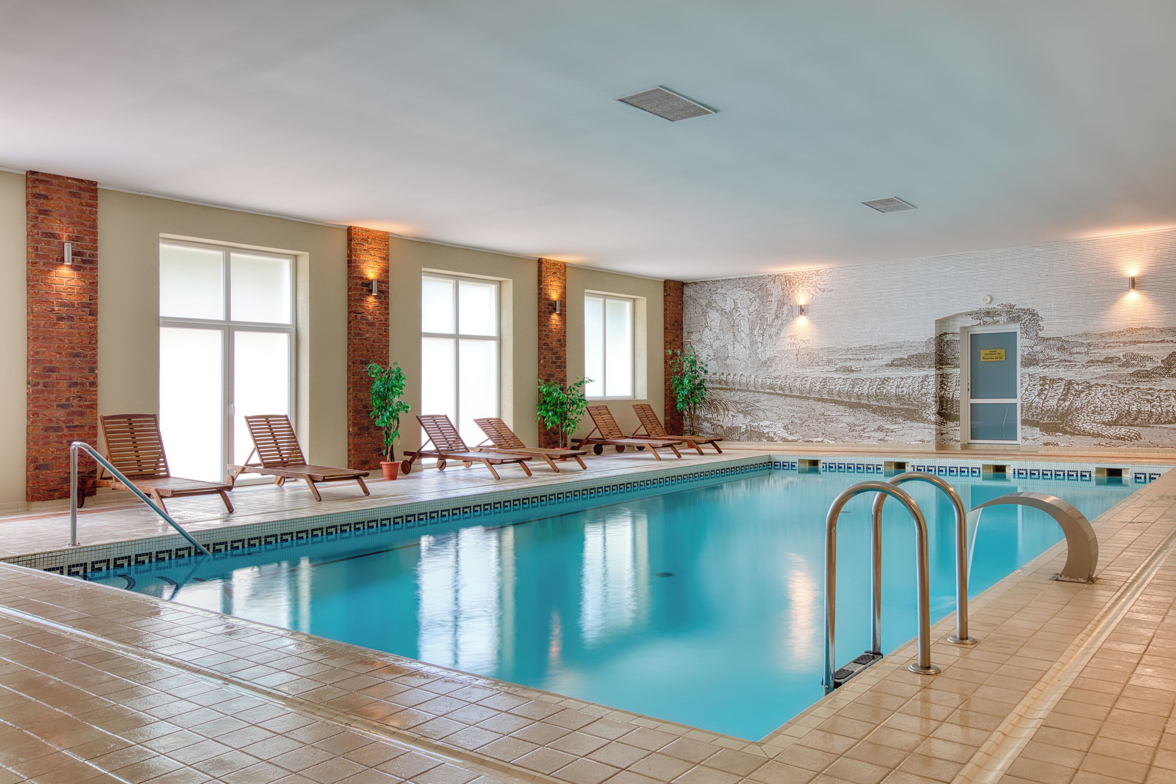 Een binnenzwembad, ligstoelen bij het zwembad