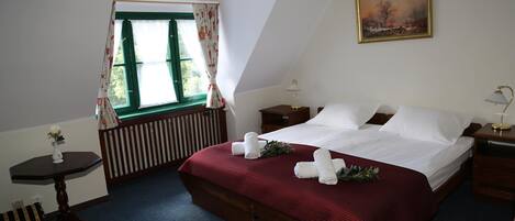A bedroom with a large bed, a window with curtains, a bedside table with a lamp, and a painting on the wall.