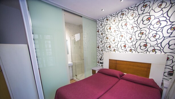 Une chambre moderne avec un grand lit, une douche en verre et un mur décoré d’un motif.