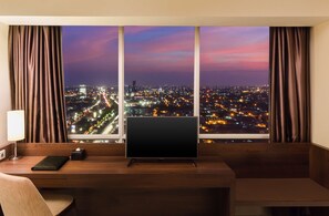 A hotel room with a large window offering a city view at dusk. - Best Western De Papilio (Surabaya)