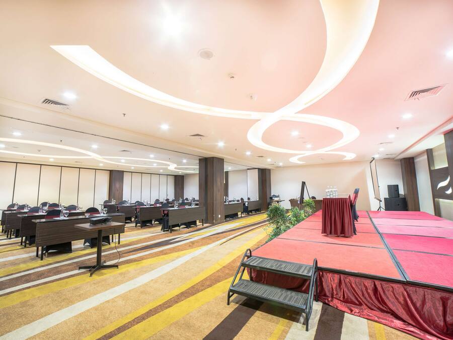 A conference room with a stage, multiple tables, and chairs.