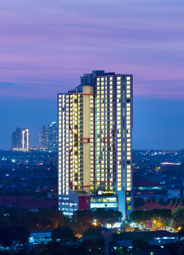 Un hotel de gran altura con múltiples pisos, un diseño vertical llamativo y ventanas iluminadas.