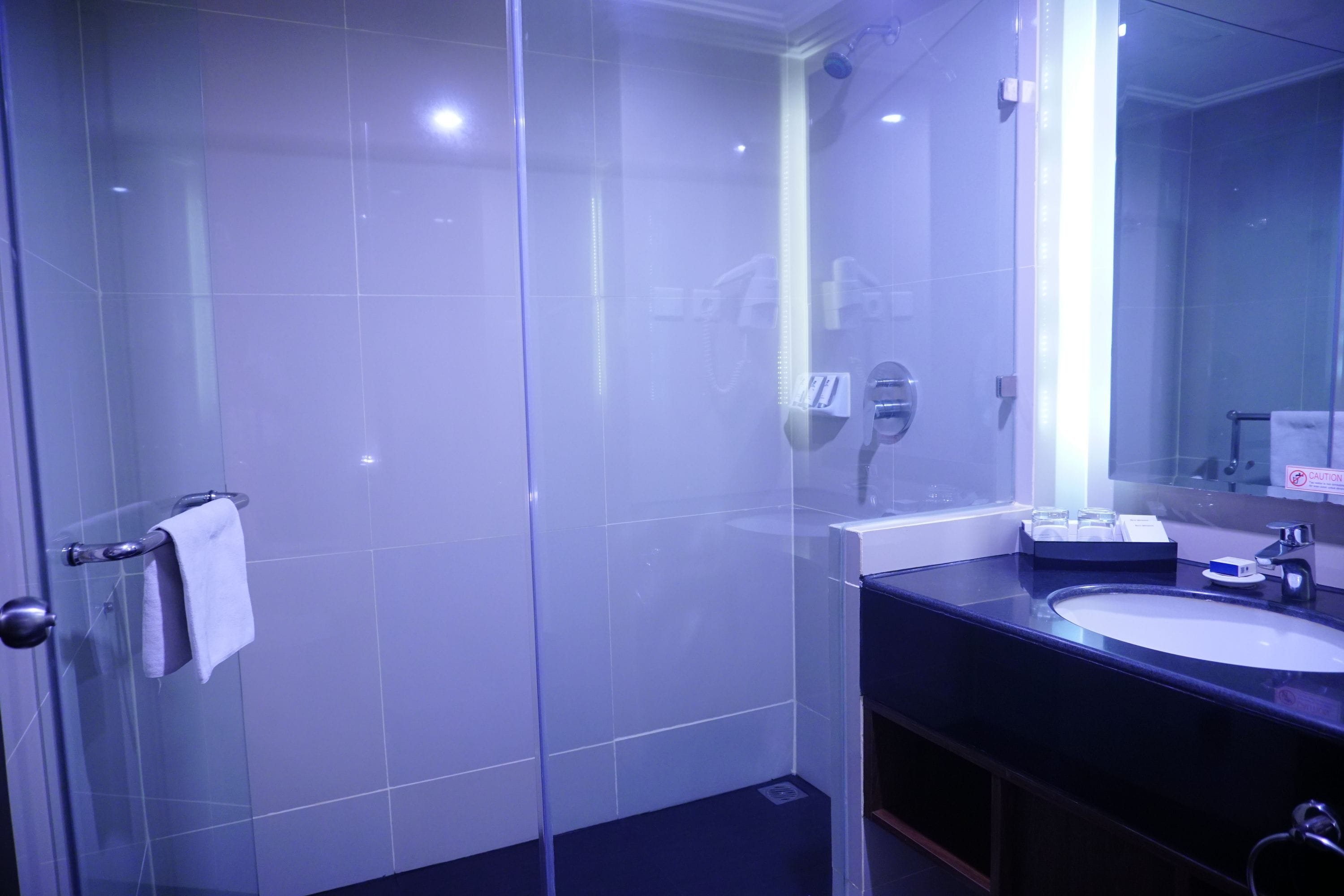 A modern bathroom with a glass shower enclosure, a sink with a mirror, and a towel rack.