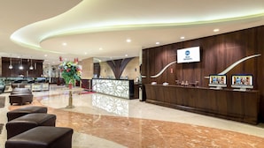 A modern hotel lobby with a reception desk, seating area, and a large decorative plant. - Best Western De Papilio (Surabaya)