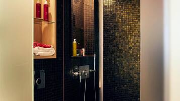 Un baño moderno con ducha de vidrio, inodoro y repisa con artículos de aseo.