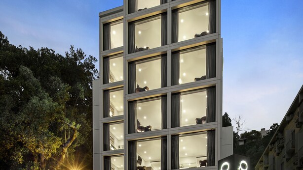 Un bâtiment moderne à plusieurs étages, doté de grandes fenêtres et d’une enseigne sur laquelle on peut lire « QUEST ».