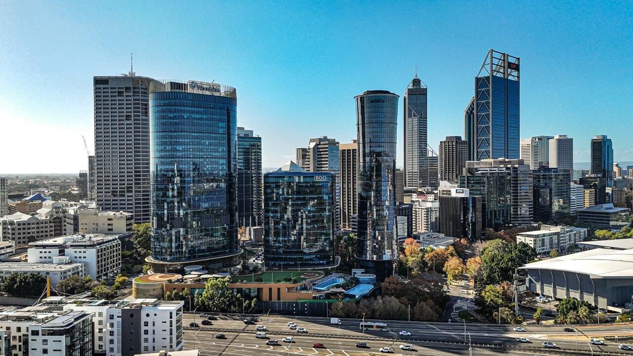 Un horizonte urbano con edificios modernos altos, una autopista y un estadio.