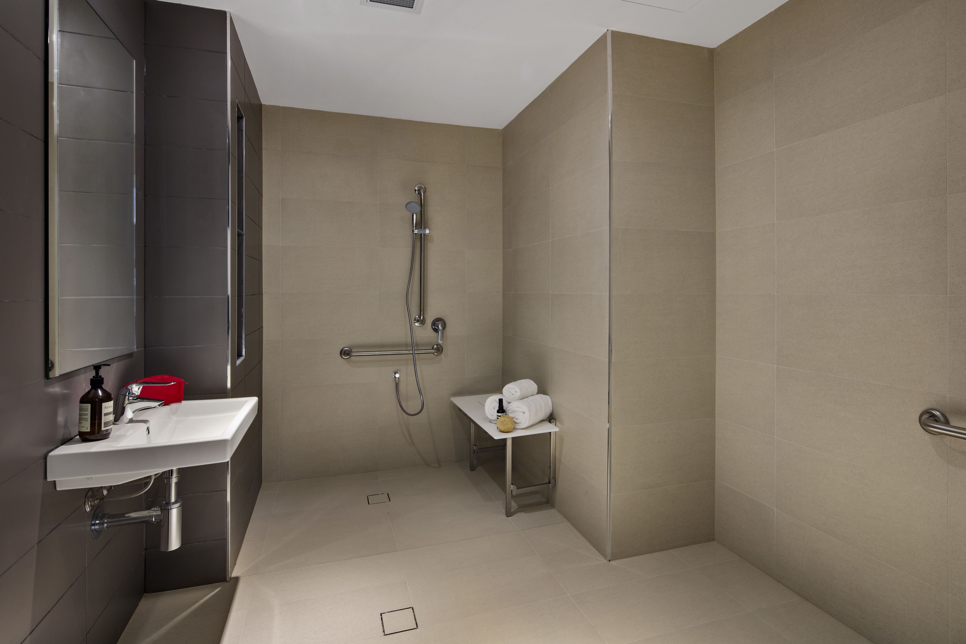 A modern bathroom with a shower, sink, and a small table with towels.