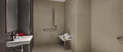 A modern bathroom with a shower, sink, and a small table with towels.
