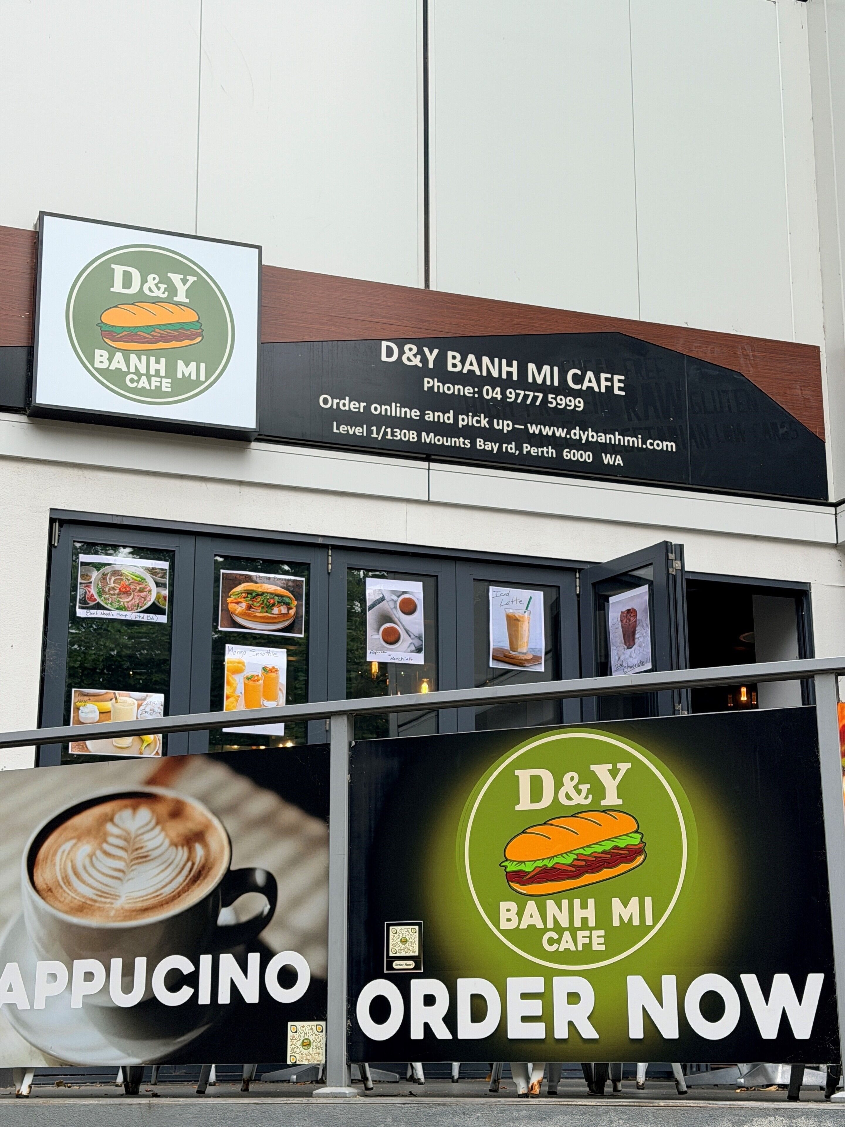 Un café D&Y Banh Mi con un cartel publicitando capuchino e invitando a ordenar ya.