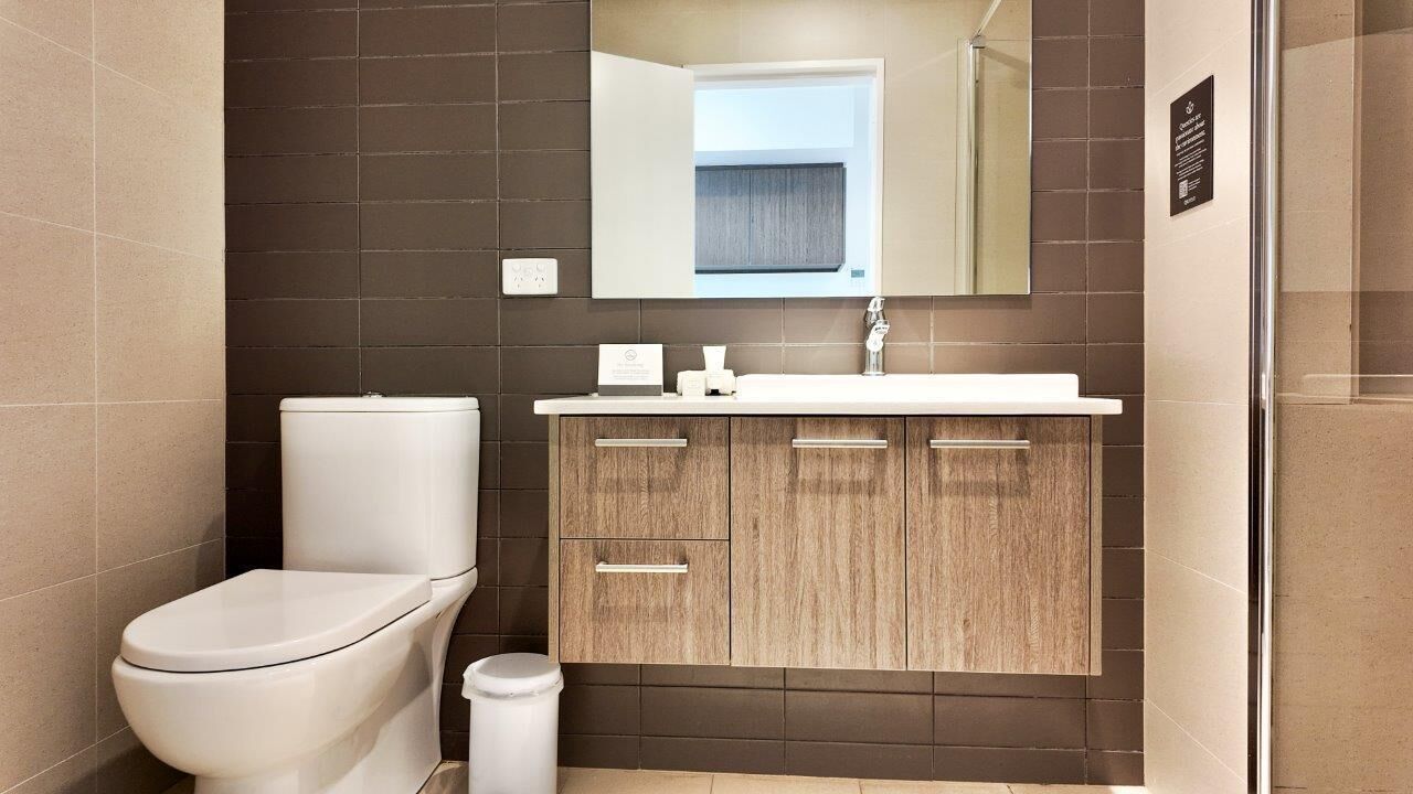 Ein modernes Badezimmer mit Toilette, Waschbecken und Spiegel.