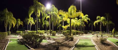 A golf course at night with illuminated trees and well-maintained greens.