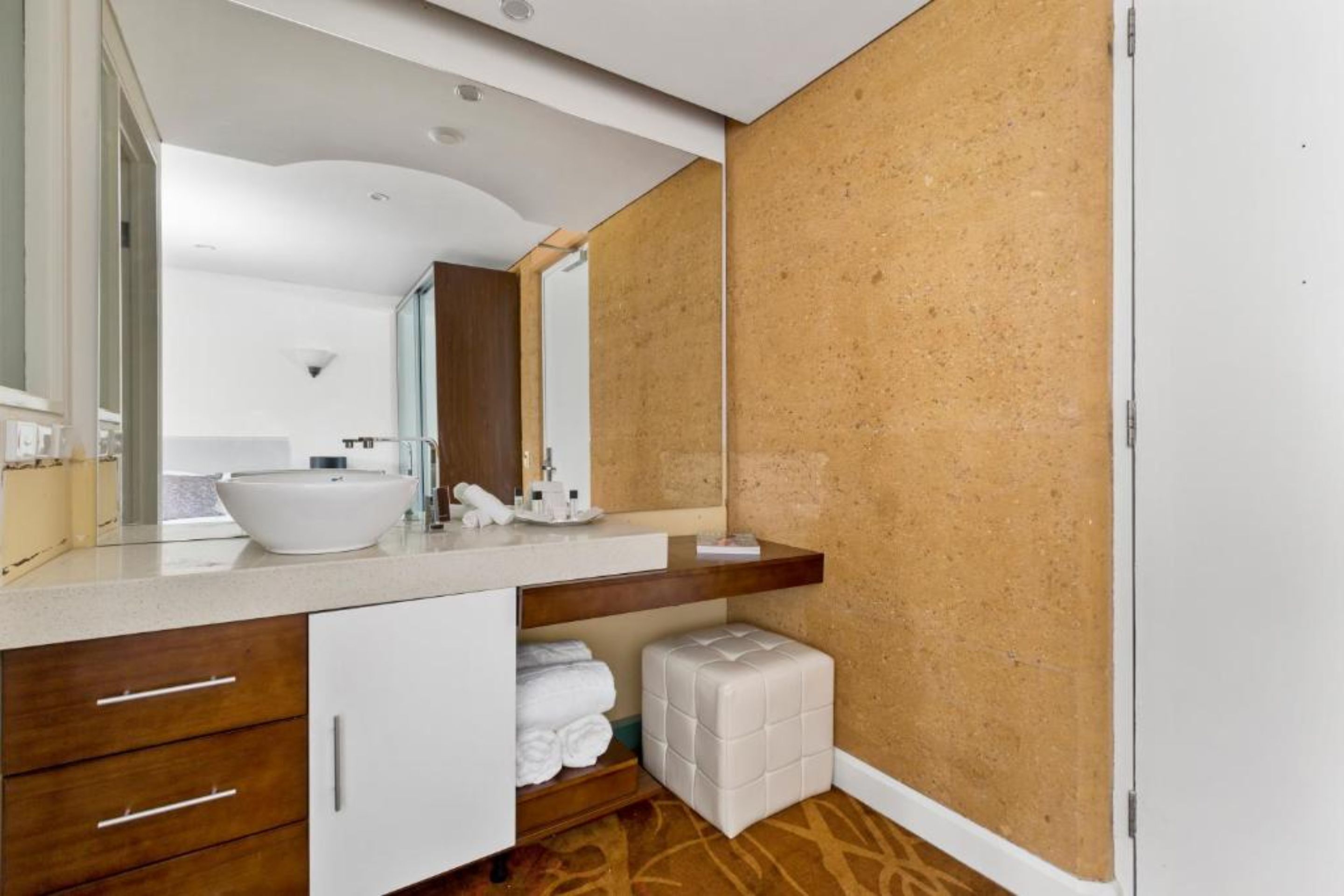 A modern bathroom with a large mirror, a white sink, and a wooden vanity.