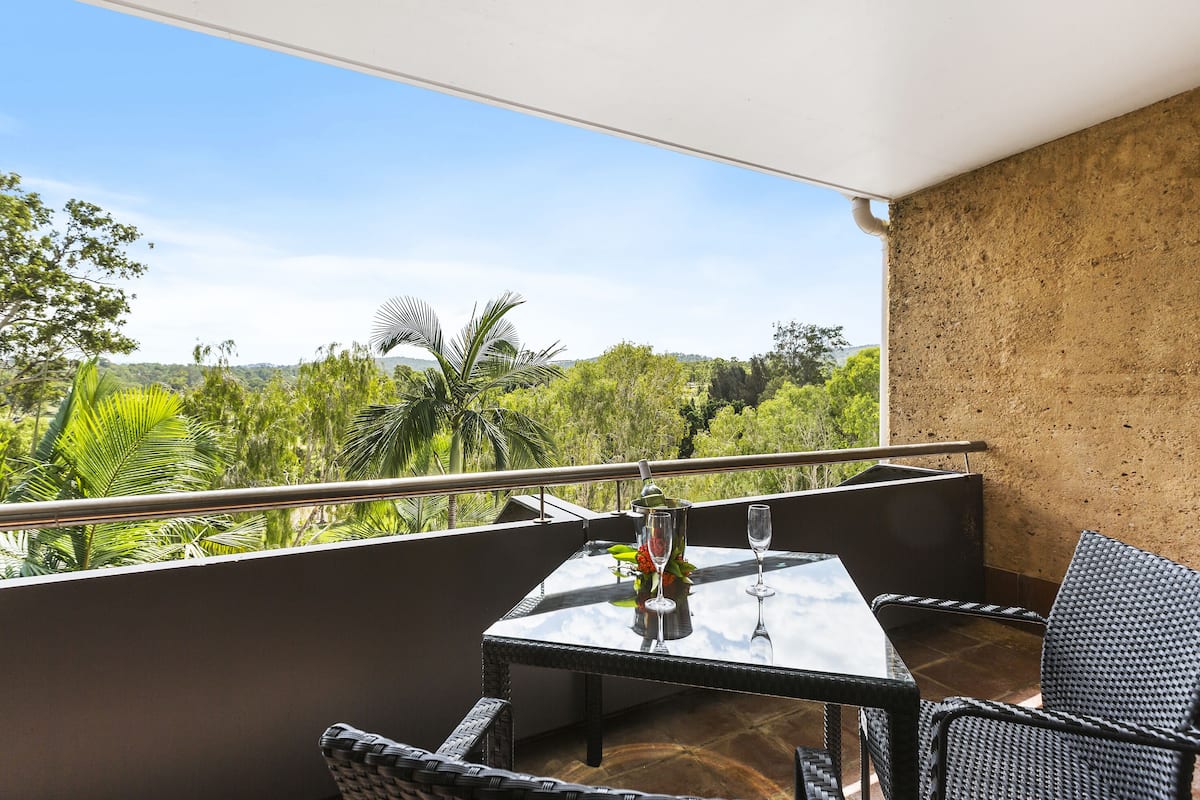 A balcony with a table, chairs, and a glass of water.
