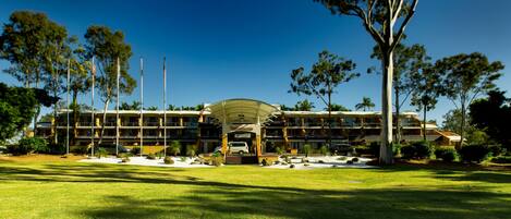 A large hotel with multiple floors, a covered entrance, and a well-maintained lawn.