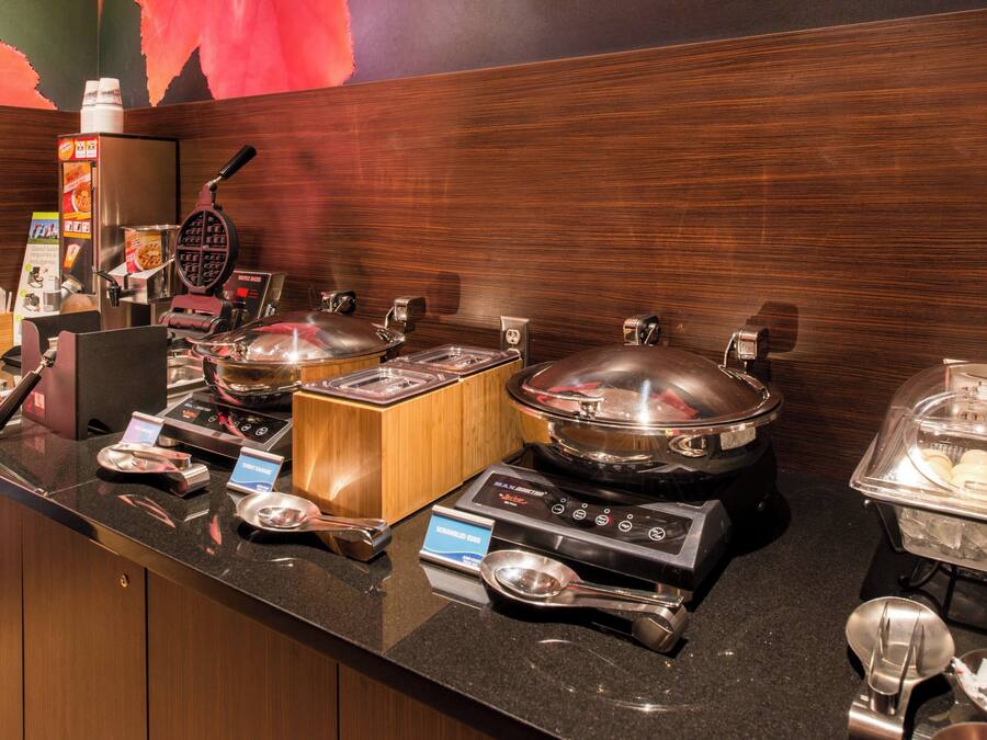A buffet setup with various food stations, including a waffle maker, hot pots, and a salad bar.