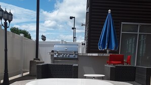 A stone hot tub with a grill, outdoor seating, and a blue umbrella. - Fairfield Inn & Suites Utica (Utica)