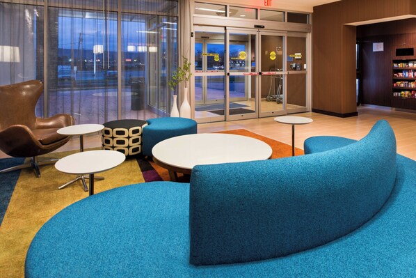 A lobby with a blue sofa, a brown leather chair, and a small table.