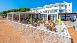 Un hôtel moderne doté d’une terrasse, d’un mur en pierre et offrant une vue sur un ciel bleu dégagé.