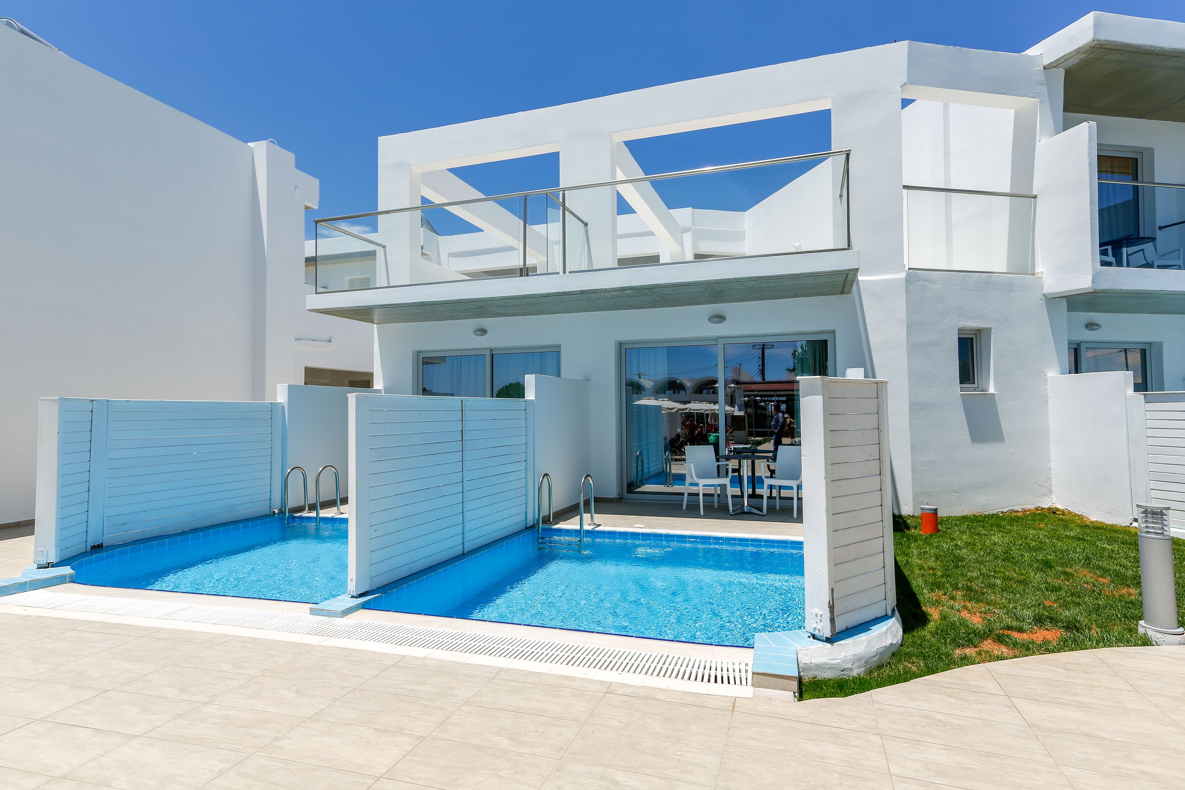 A modern building with a swimming pool, outdoor seating, and a covered patio area.