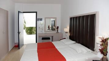 Une chambre d’hôtel avec un lit, un bureau, un miroir, une fenêtre et une porte.