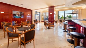 Un restaurant spacieux avec des chaises et des tables en bois, un coin bar et de grandes fenêtres donnant sur un paysage agréable.