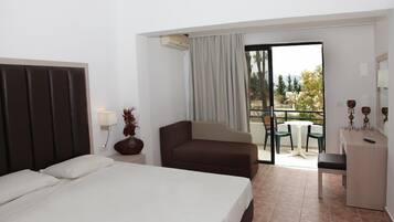 A hotel room with a bed, a sofa, a desk, and a balcony with a table and chairs.