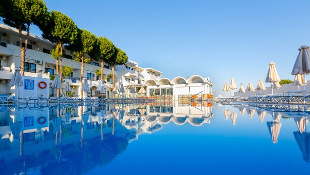 Un hôtel doté d’une piscine, de plusieurs étages et offrant une vue sur un ciel d’un bleu éclatant.