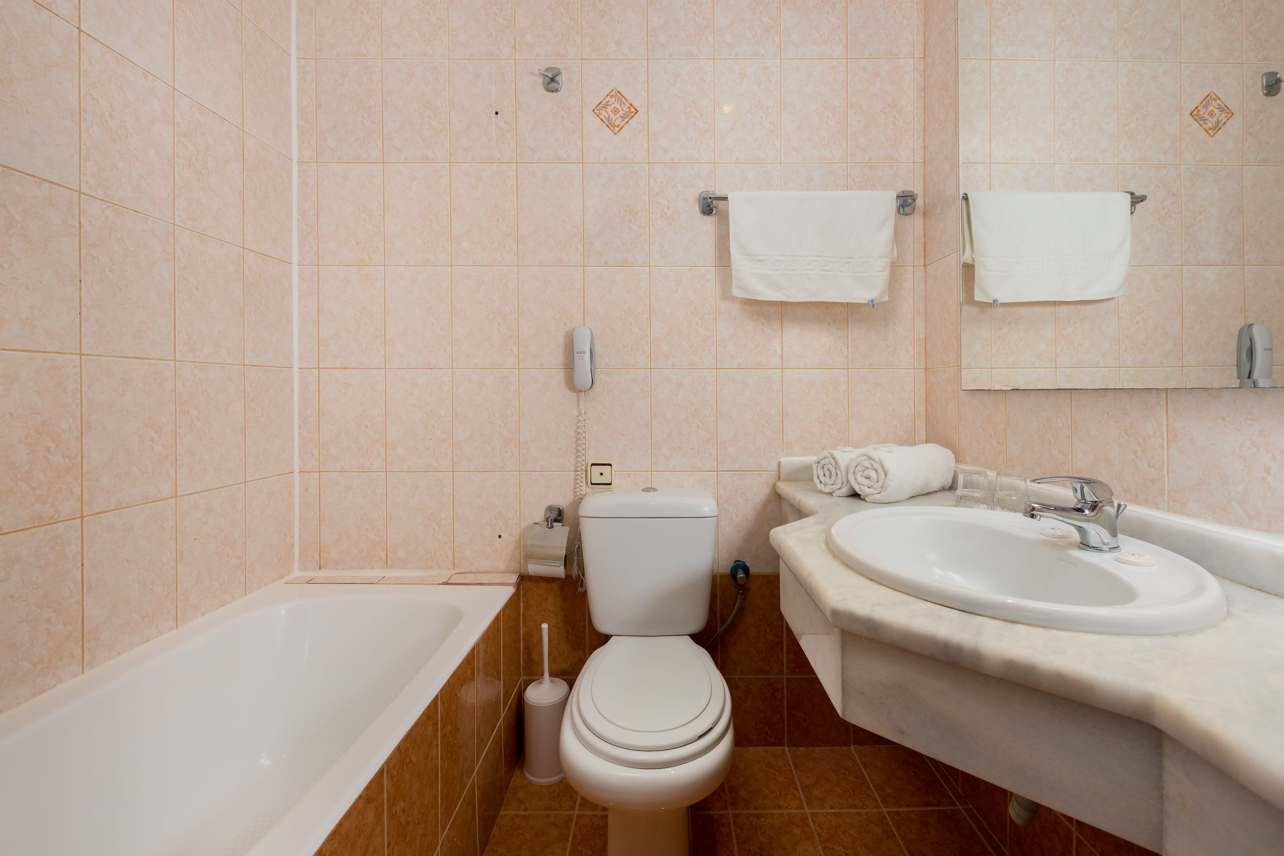 A bathroom with a bathtub, toilet, sink, and towel racks.