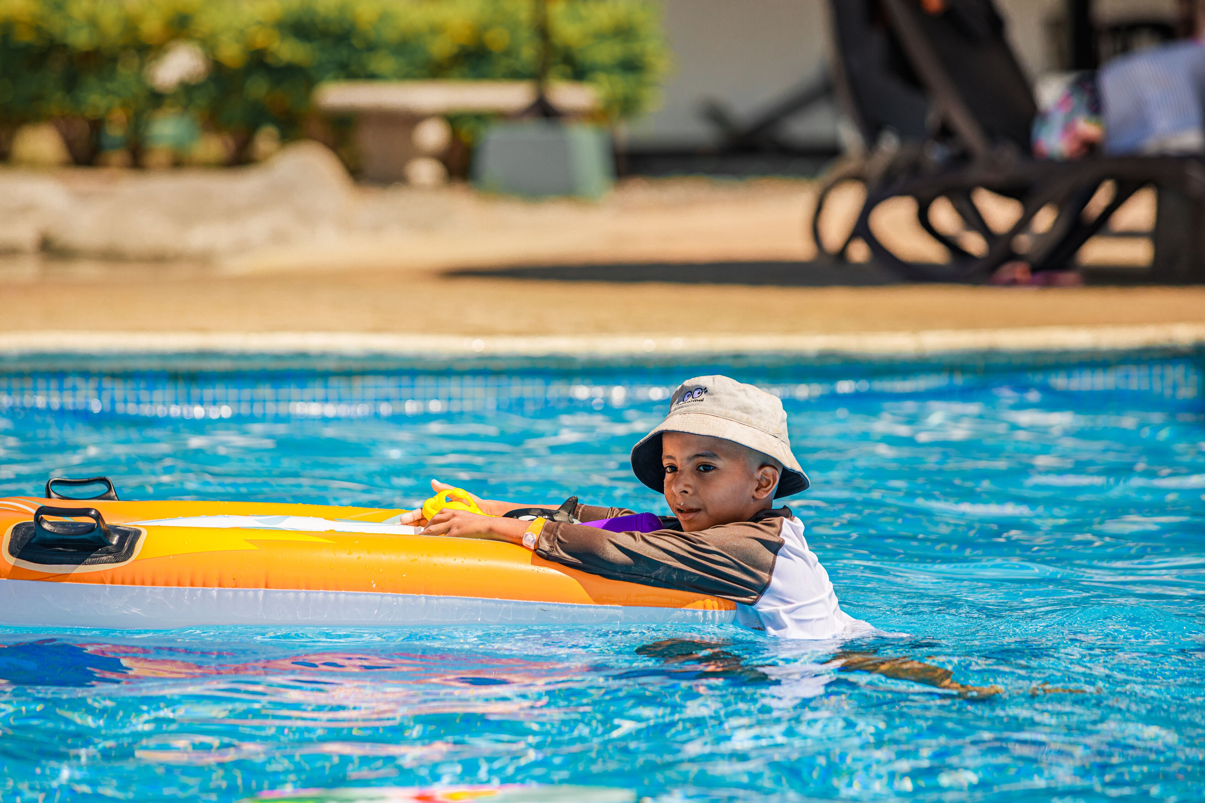 A child in a swimming pool using an inflatable raft.