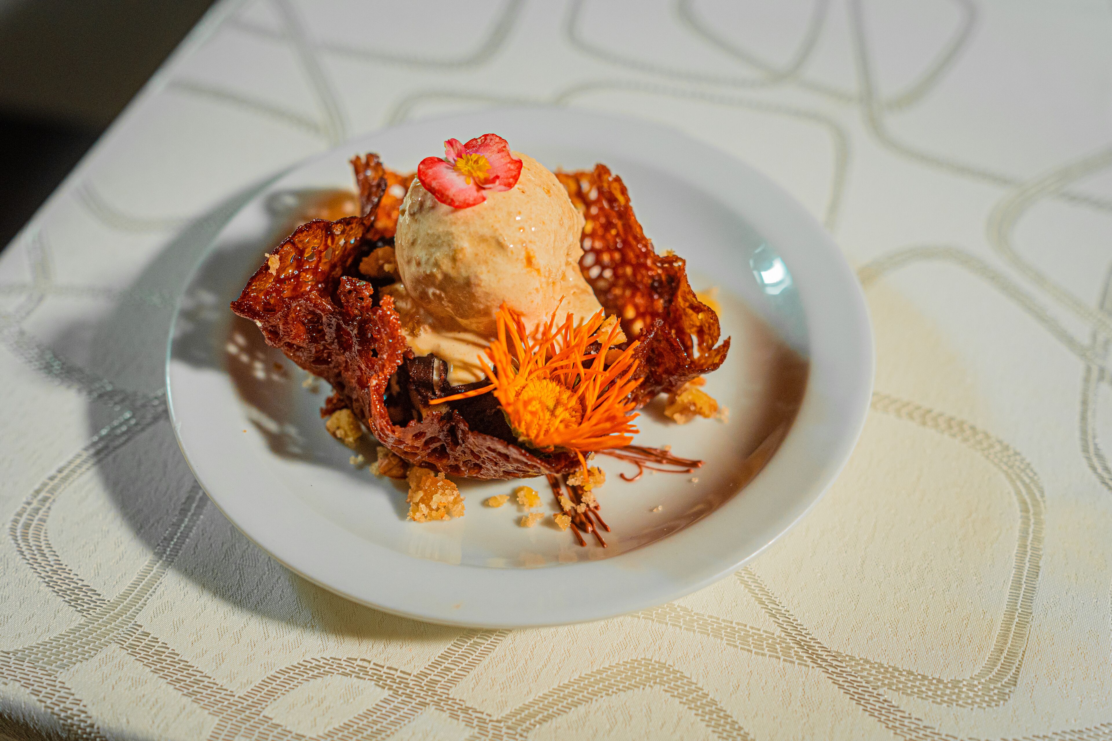 Ein Dessert auf einem weißen Teller mit einer gemusterten Tischdecke.