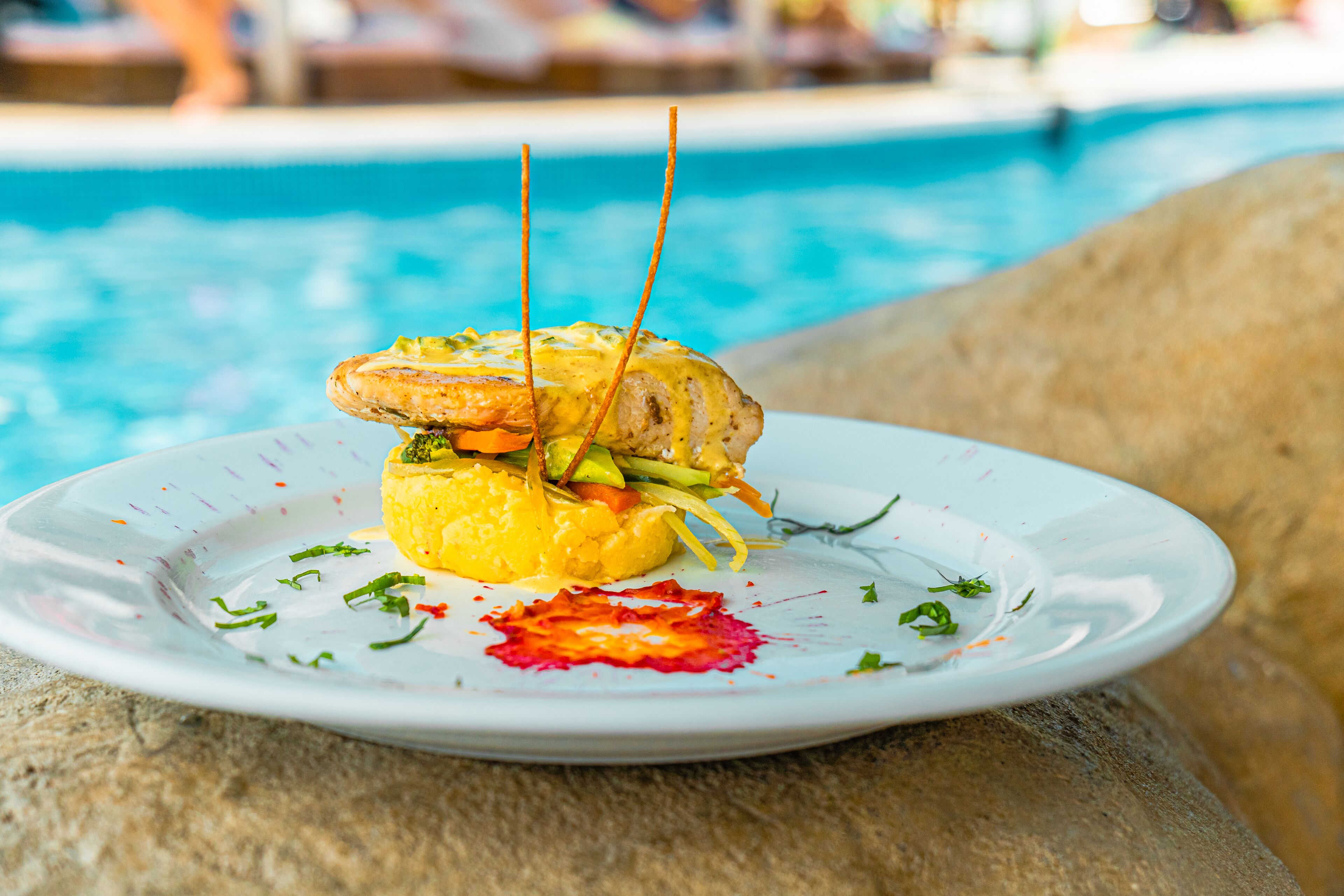 Une assiette de nourriture avec une piscine en arrière-plan.