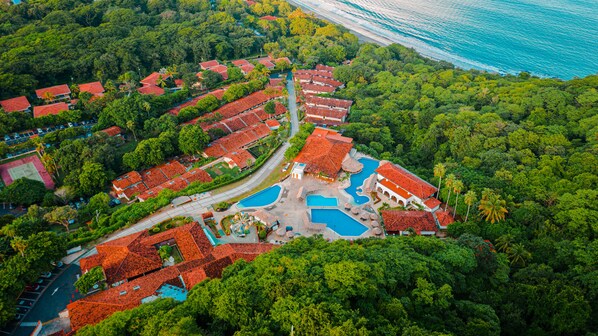 An aerial view of a resort with multiple buildings, a swimming pool, and a beach. - Condovac la Costa (Sardinal)