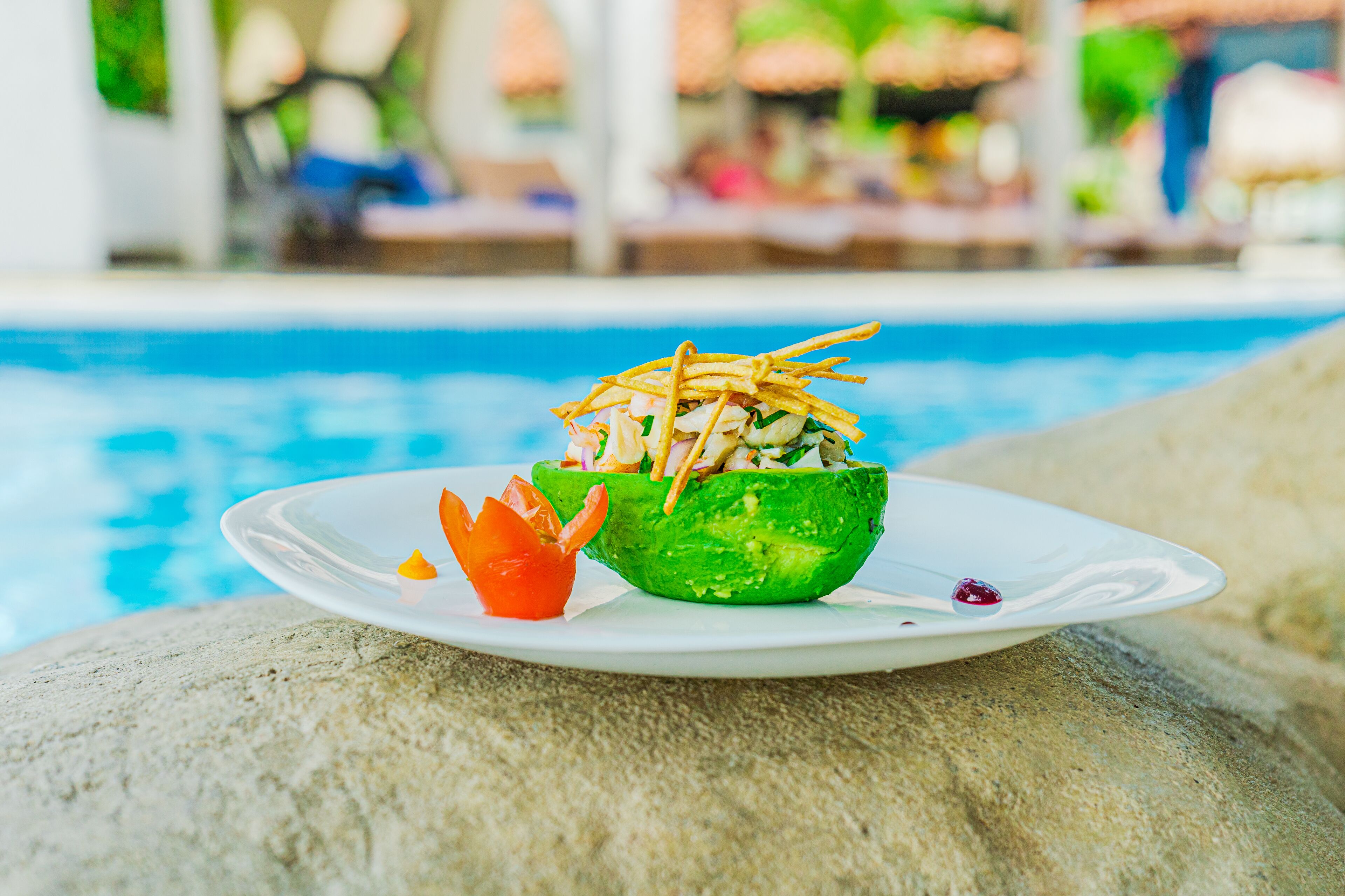A plate with a salad on a rock by a pool.