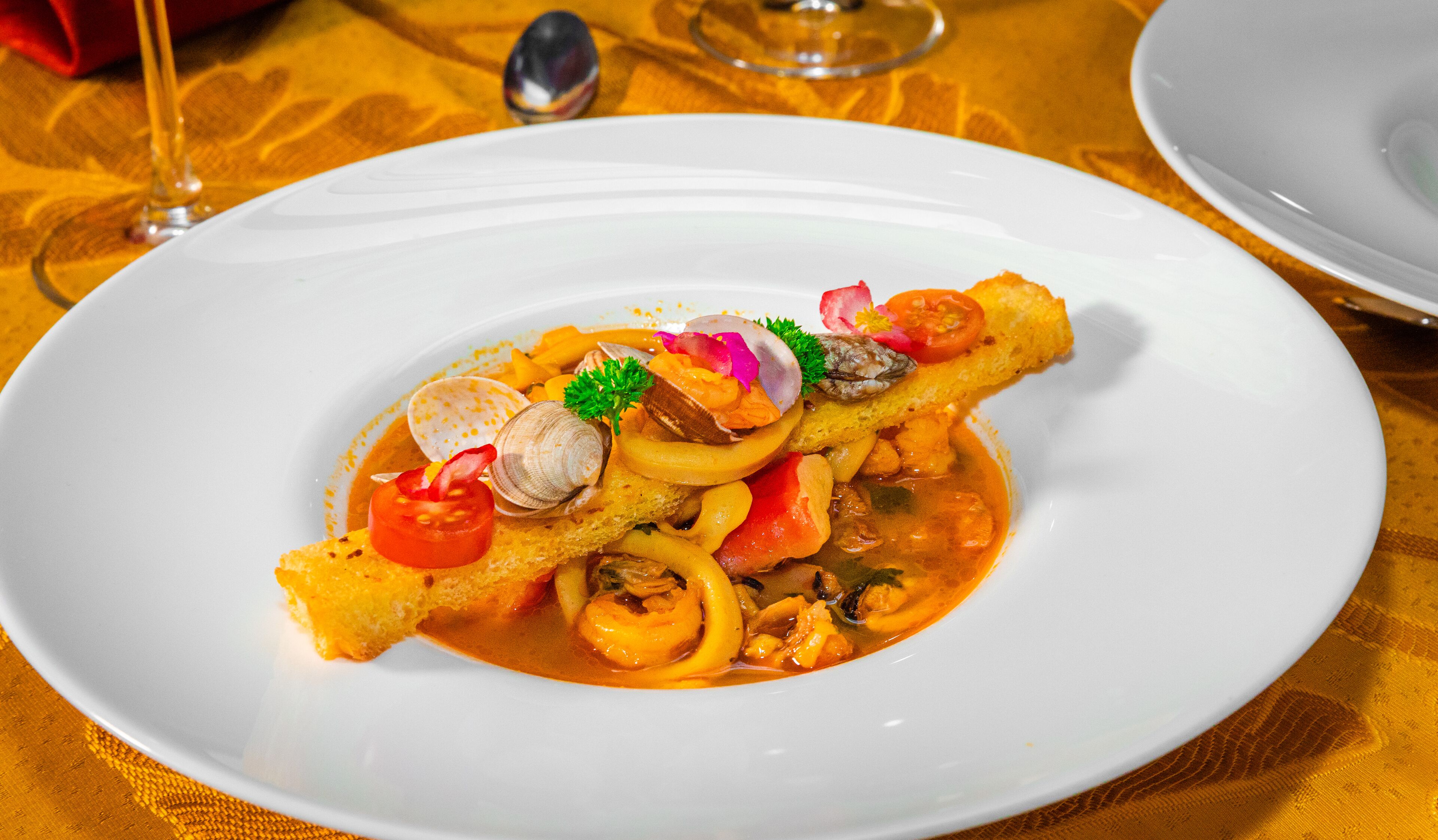 Un plato de mariscos sobre un mantel blanco y dorado.