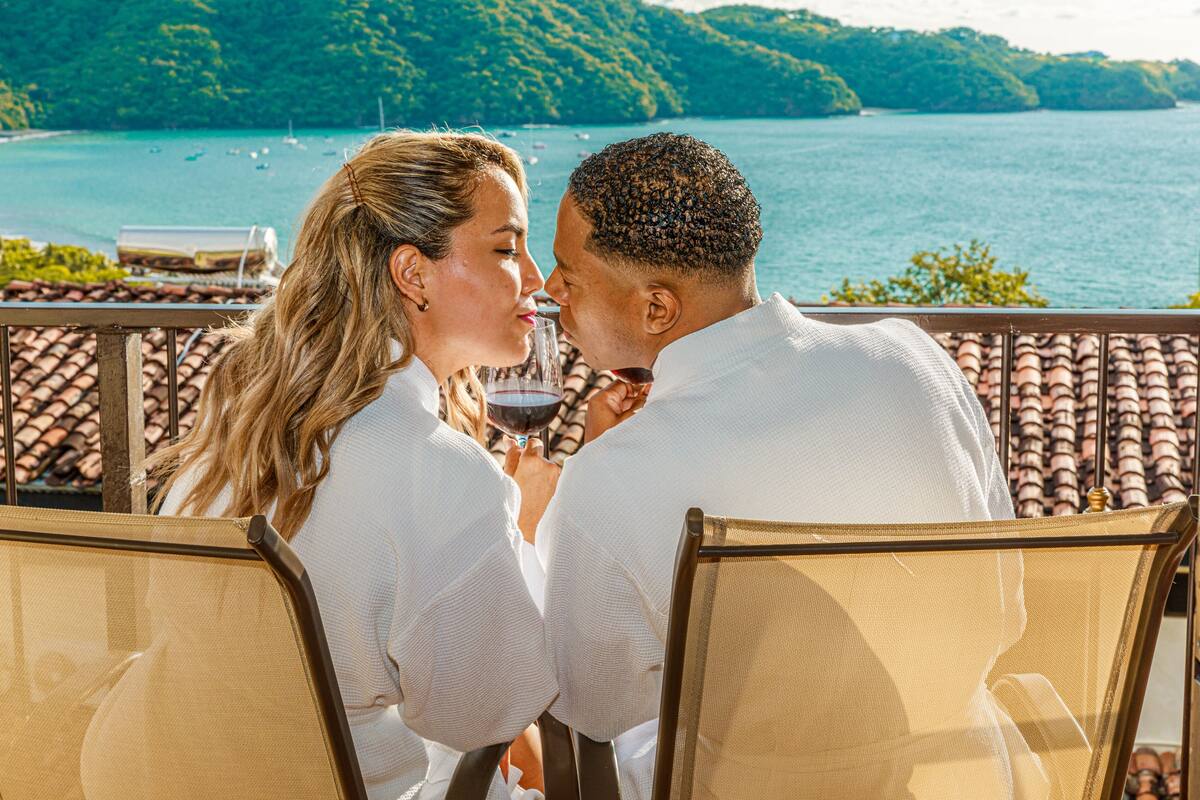 A couple seated at a table with a view of a lake and hills.