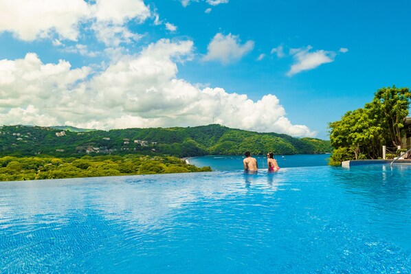 Una amplia piscina infinita con vistas despejadas del paisaje circundante y las colinas.