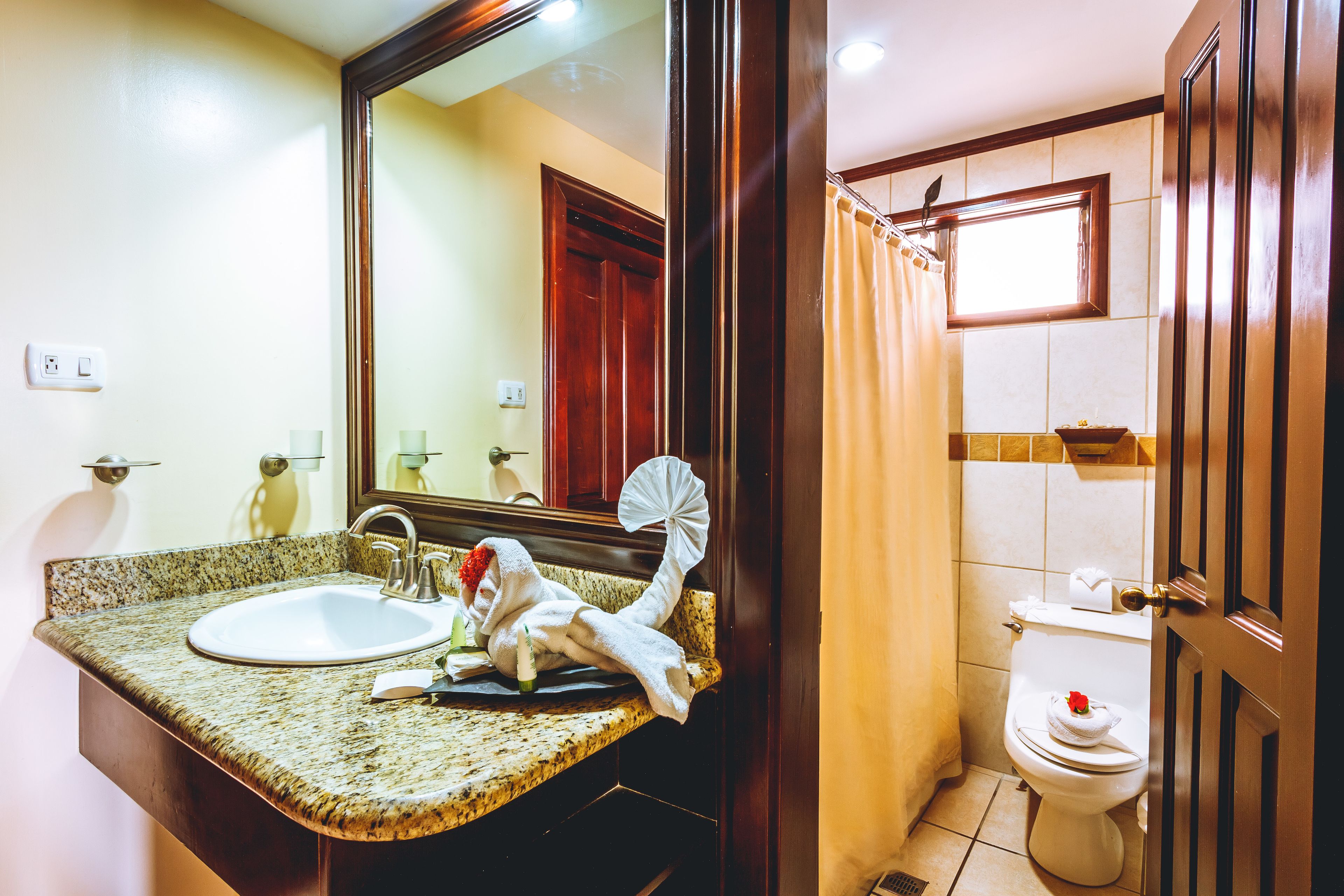 A bathroom with a granite countertop sink, a mirror, a towel, and a toilet.