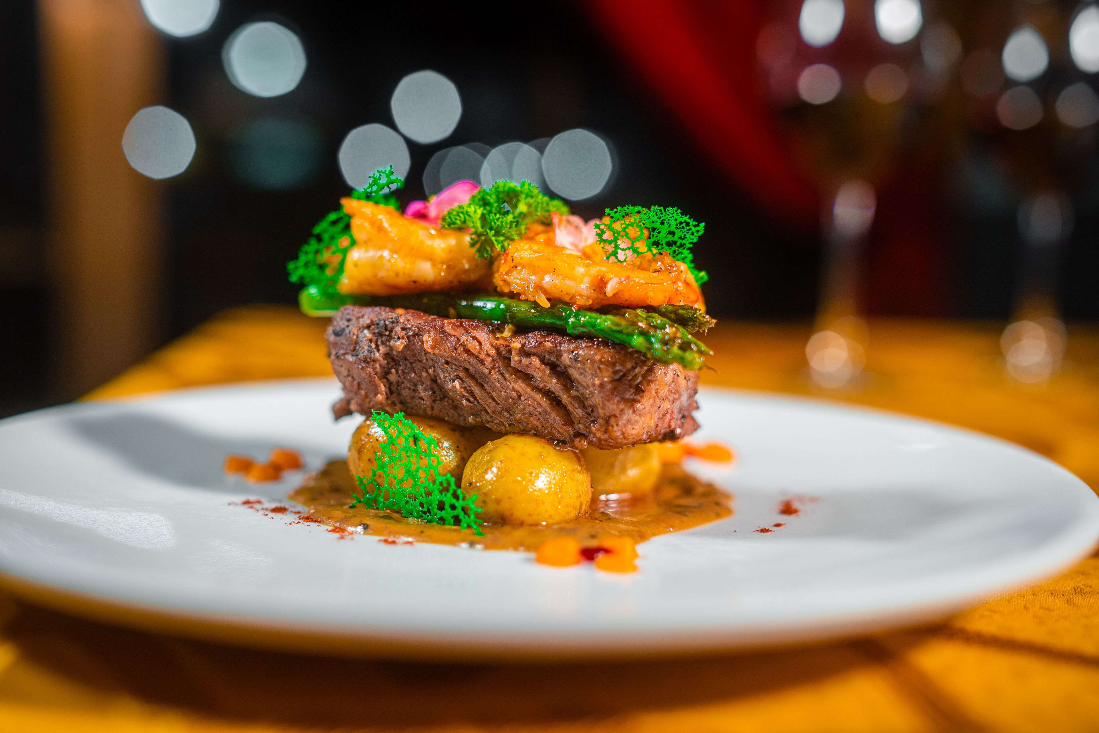 A plated dish with meat, vegetables, and sauce, presented on a white plate.