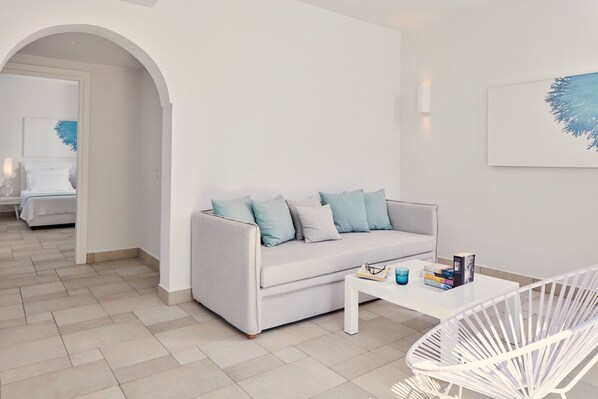 A modern living room with a white sofa, a white coffee table, and a white chair.