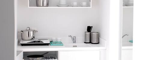 A compact kitchen with white cabinetry, a built-in oven, a microwave, and a small refrigerator.